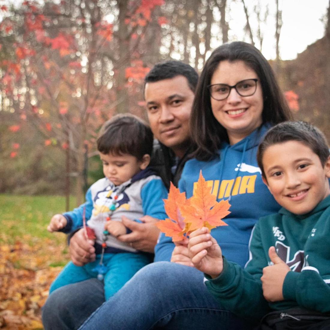 Pastor Wellington Mariano with his family, sitting together among autumn leaves